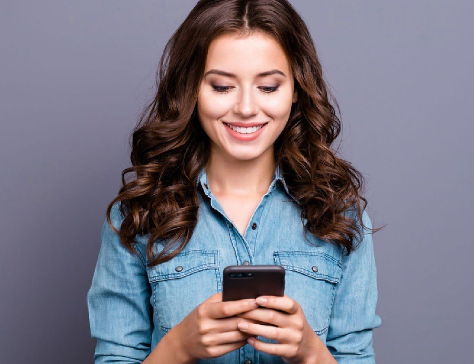 Image of a smiling model girl checking her mobile phone